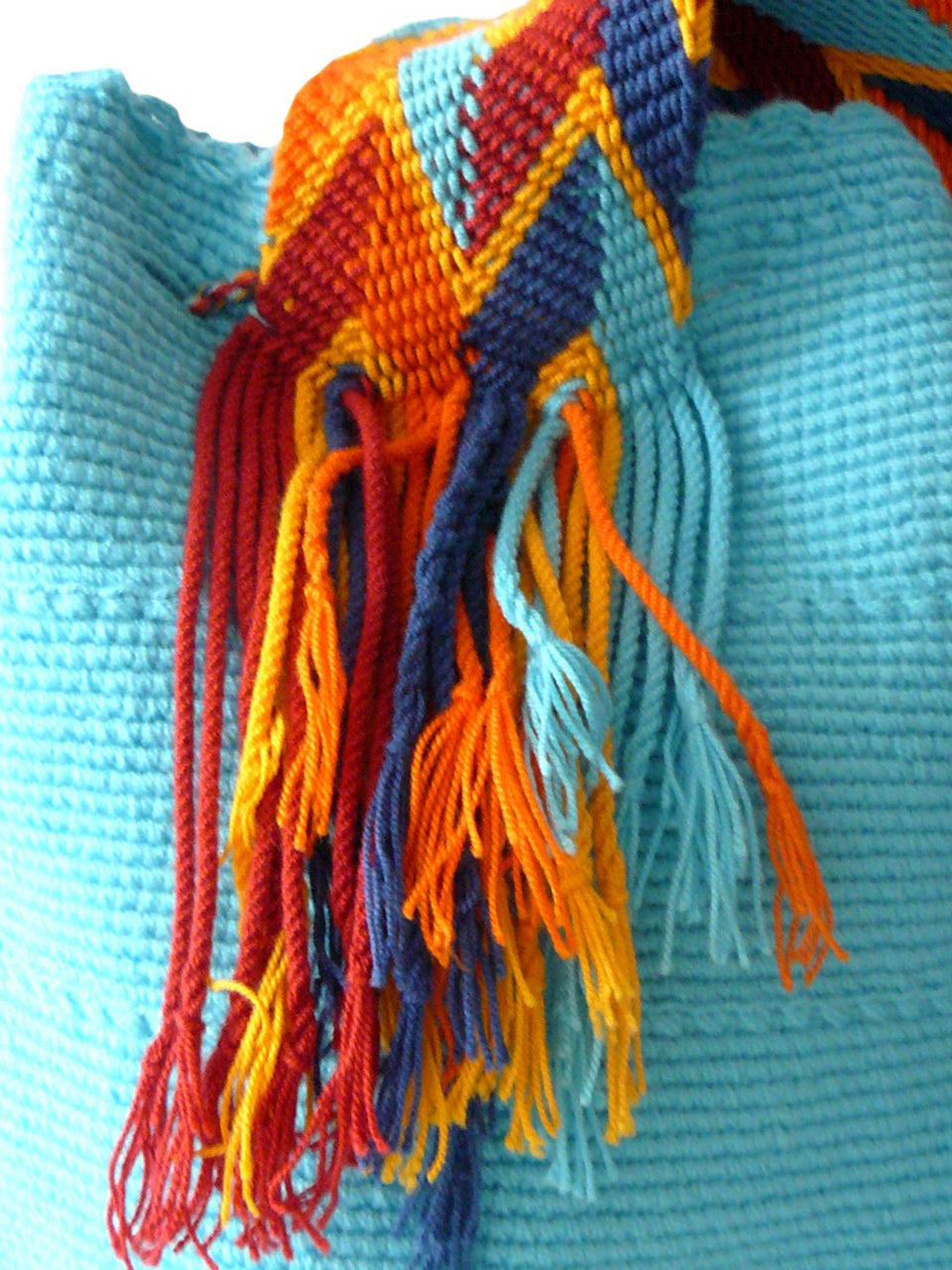 Turquoise woven shoulder bag with blue, orange, and yellow tassels Palmazul Beachwear Wayuu Mochila